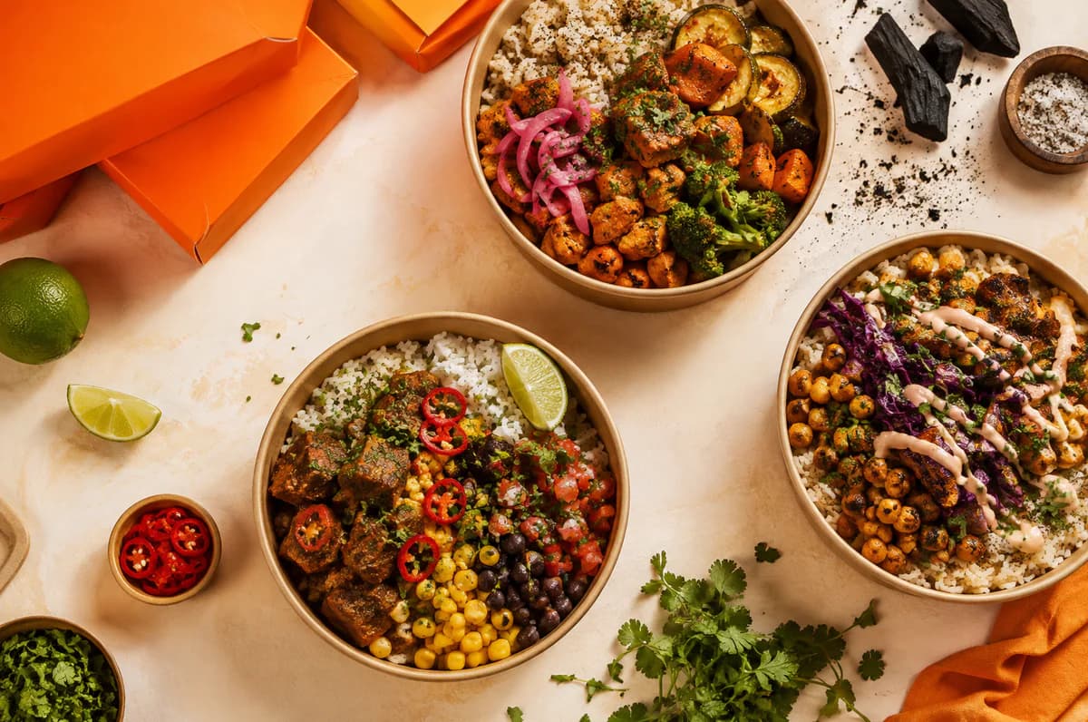 Fresh colourful comfort-food bowls arranged with herbs and orange packaging